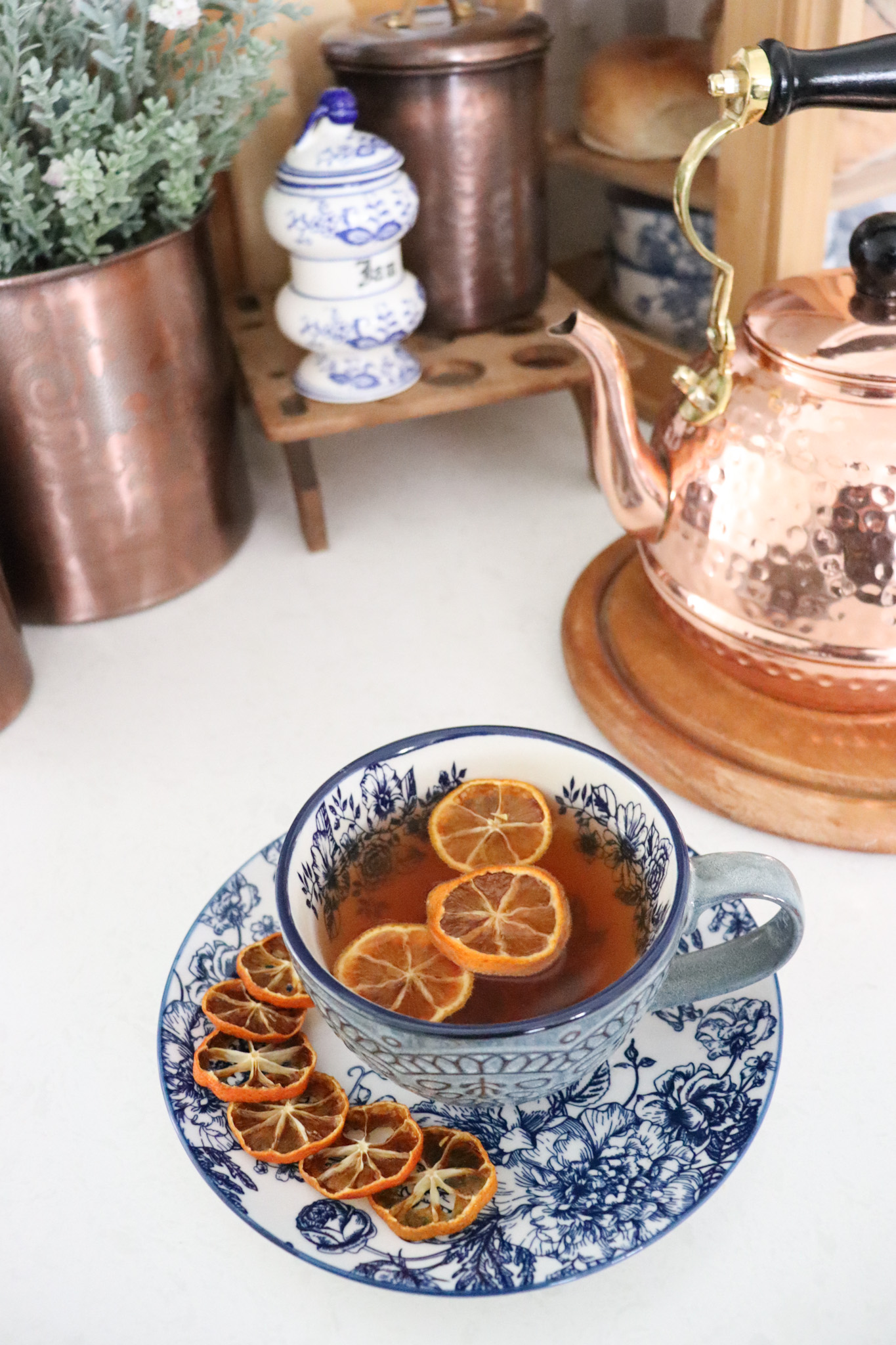 Drinking a hot cup of orange tea from blue and white floral dishes.